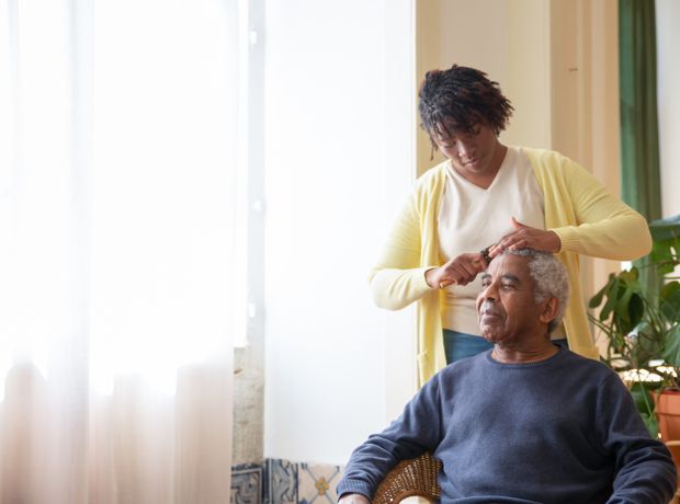 A care worker tending to an older client beside a sunlit window