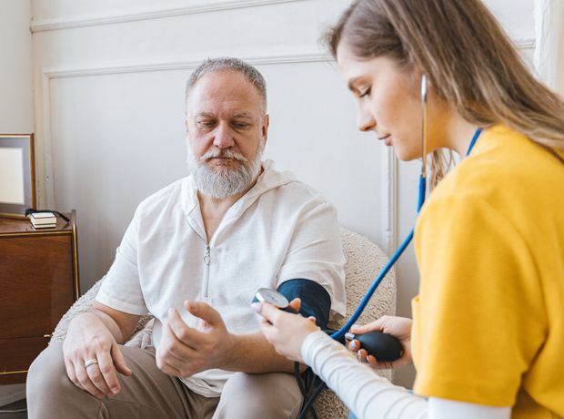 A nurse taking an older patient's blood pressure at his home